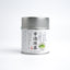 A tin can of Kamitsujien Uji Matcha green tea powder with Japanese text and a picture of a tea leaf on the label.