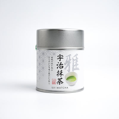 A tin can of Kamitsujien Uji Matcha green tea powder with Japanese text and a picture of a tea leaf on the label.