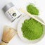 A tin can of Kamitsujien Uji Matcha green tea powder with Japanese text and a picture of a tea leaf on the label.