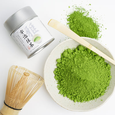 A tin can of Kamitsujien Uji Matcha green tea powder with Japanese text and a picture of a tea leaf on the label.