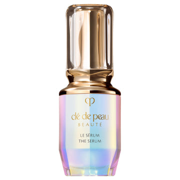 A bottle of Shiseido Clé de Peau Beáuté The Serum with a clear, rose gold, and silver label.